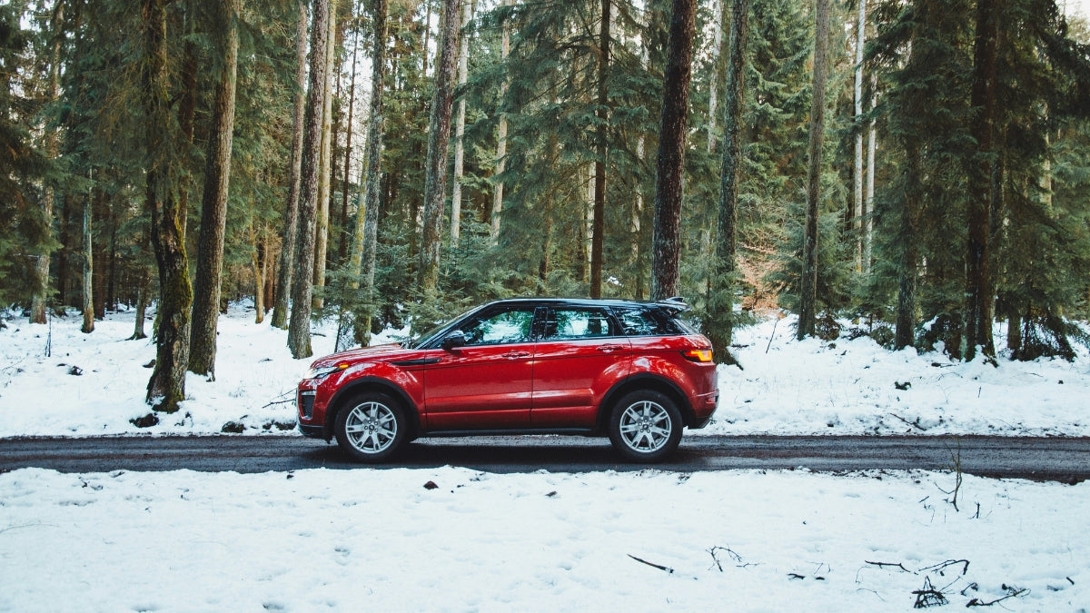 Red SUV on a snowy winter road, demonstrating the importance of reliable car battery performance in cold weather.